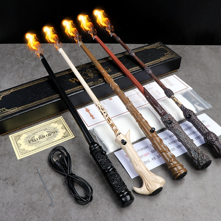 A set of decorative torches with flames, a Harry Potter magic wand with a box, and a small item on a grey surface. 